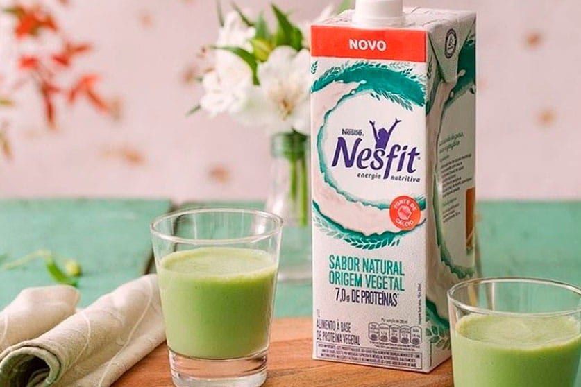 Uma embalagem de bebida vegetal Nesfit sabor natural. Nos dois lados da embalagem, há dois copos cheios da bebida.